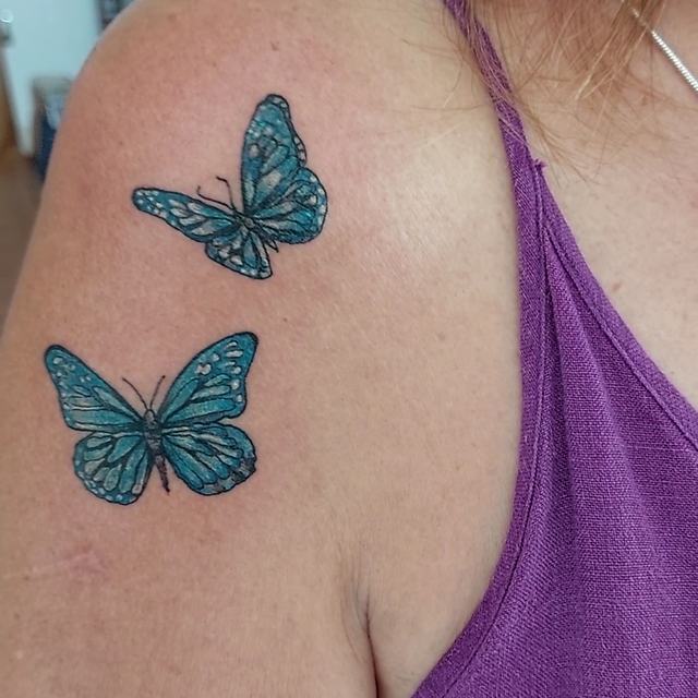 Two blue butterflies on a shoulder